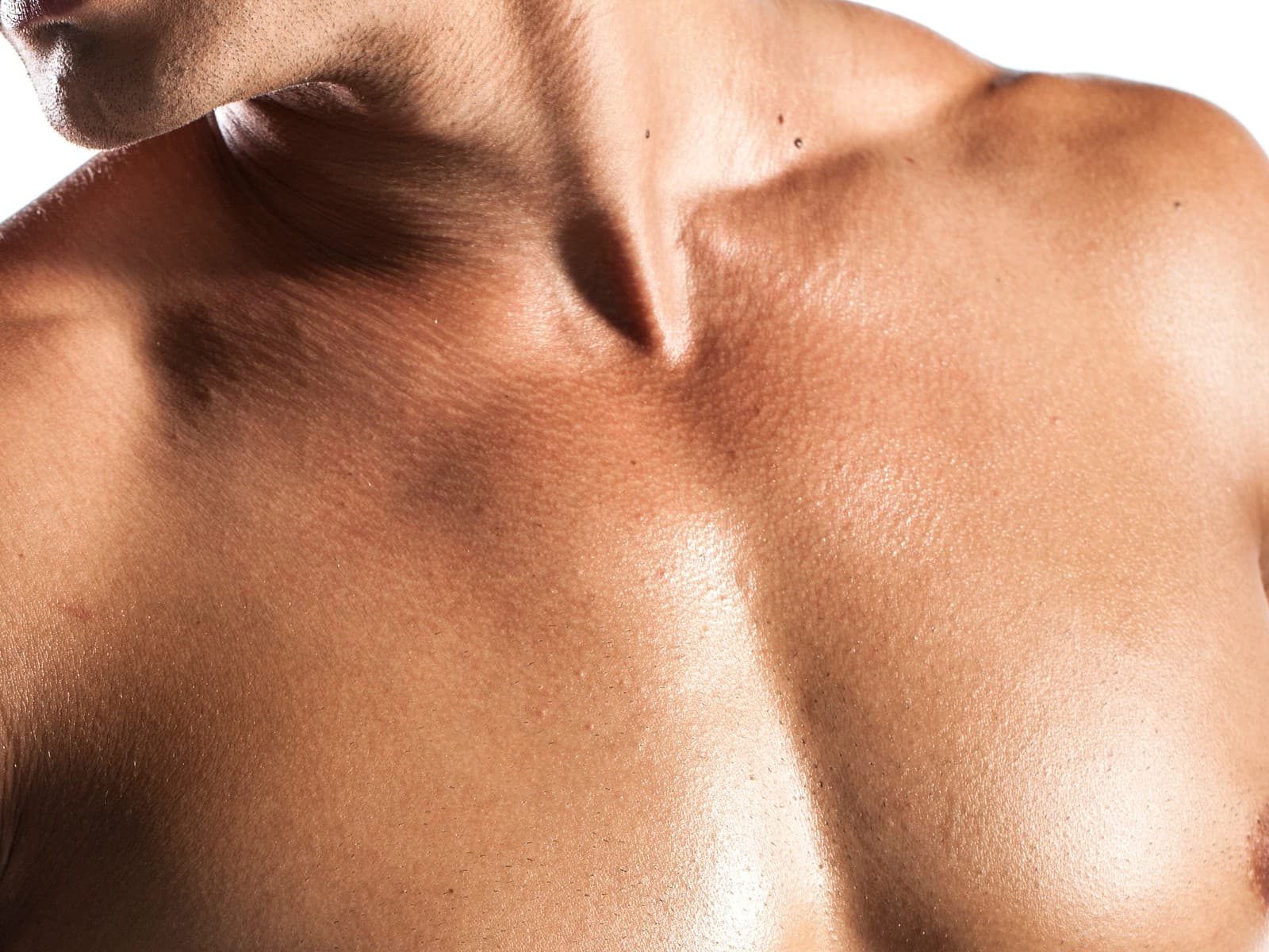 A man's bare chest and shoulder against a pale ground, the skin smooth and hair-free