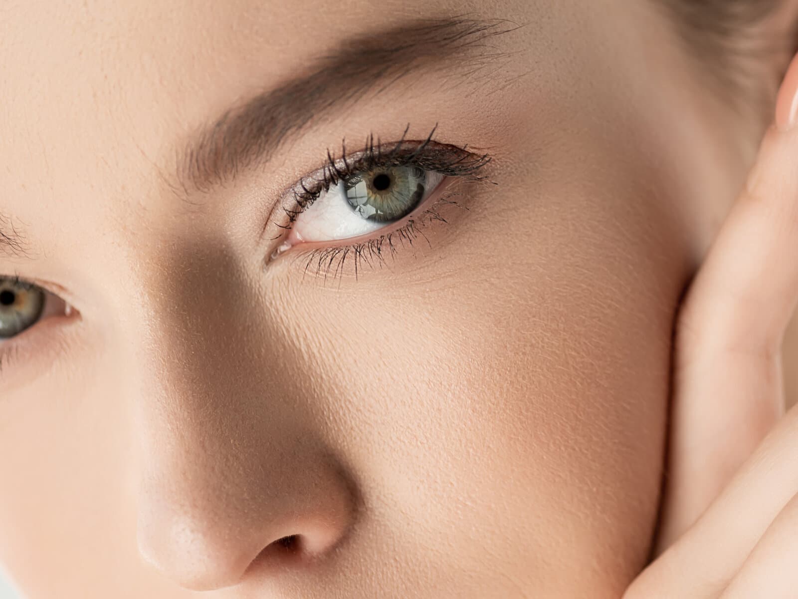 A close view of a woman's cheek and eye, the surface of the skin fine and even