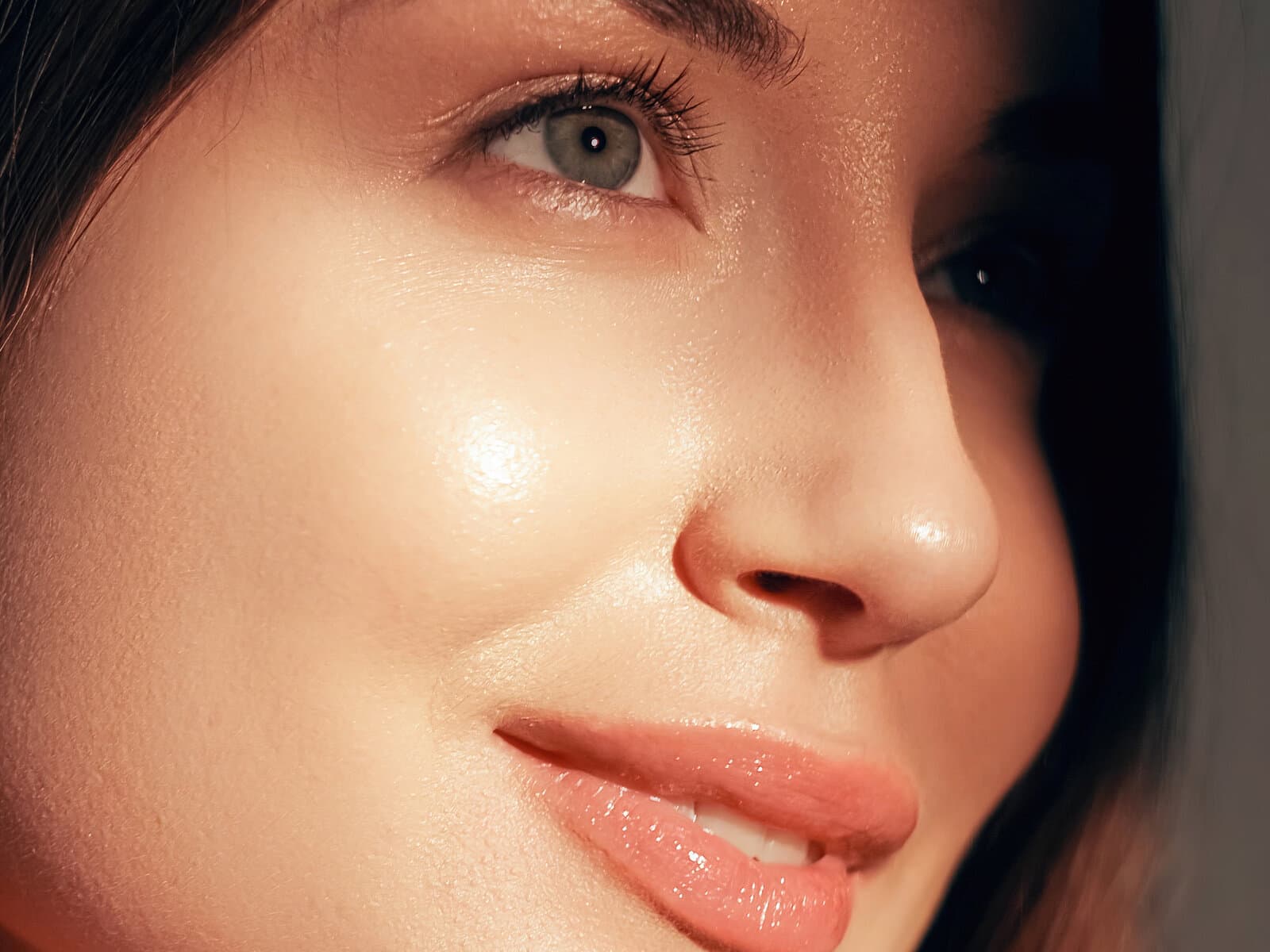 A close three-quarter view of a woman's cheek and mouth, the skin bright and freshly polished
